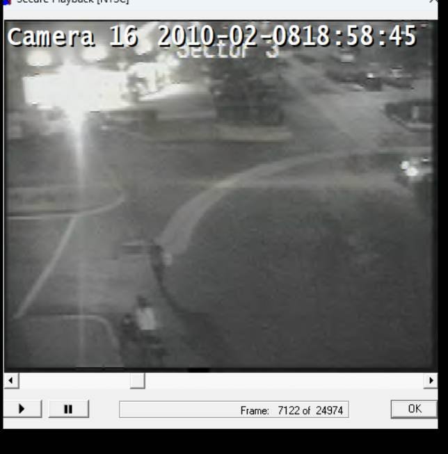 (Image 6) Camera 16 — 18:58:45. The group again in the same general area, moving toward the border crossing. The timestamp is just over an hour after the previous frame. The light-colored upper body in the lower center is the light coat that recurs across the sequence.