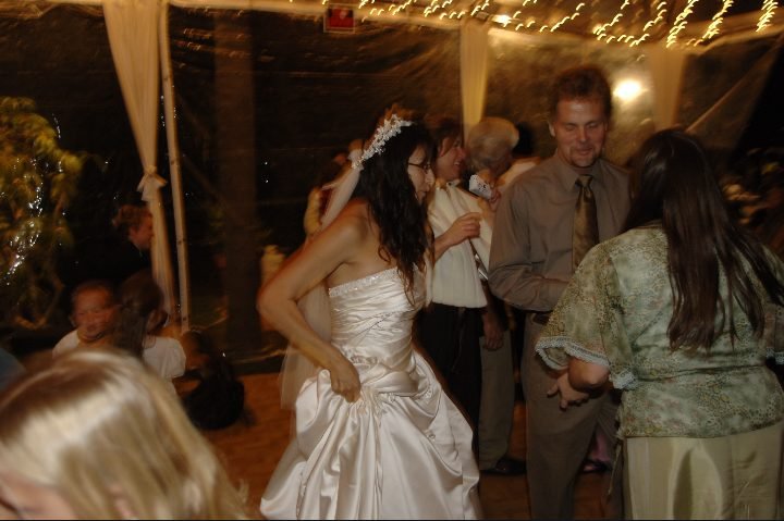 Summer in her wedding dress dancing beside Chase Merritt and Cathy Jarvis under a canopy of string lights at Joseph and Summer's wedding reception