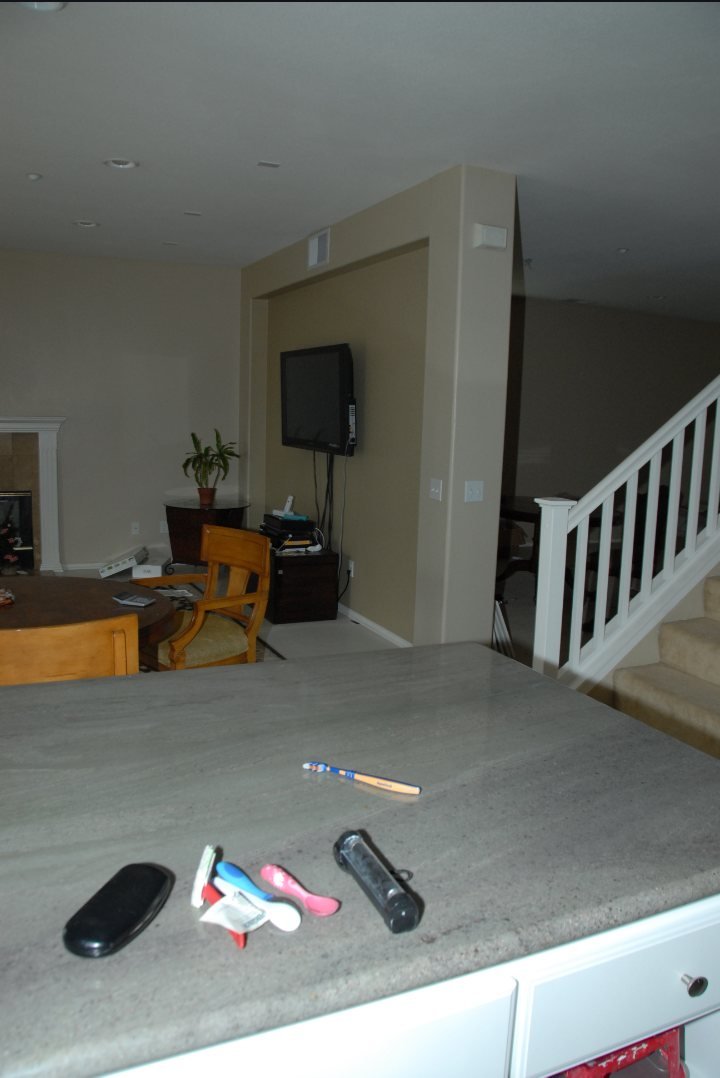 Trial Exhibit 47 — the McStay kitchen island countertop with a black light lying beside a toothbrush, children's utensils, and an eyeglass case; the family room and staircase behind